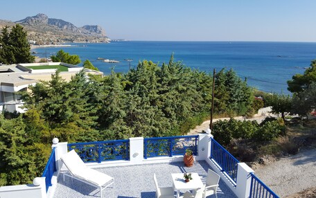A terrace with a view of the sea, surrounded by trees and buildings.