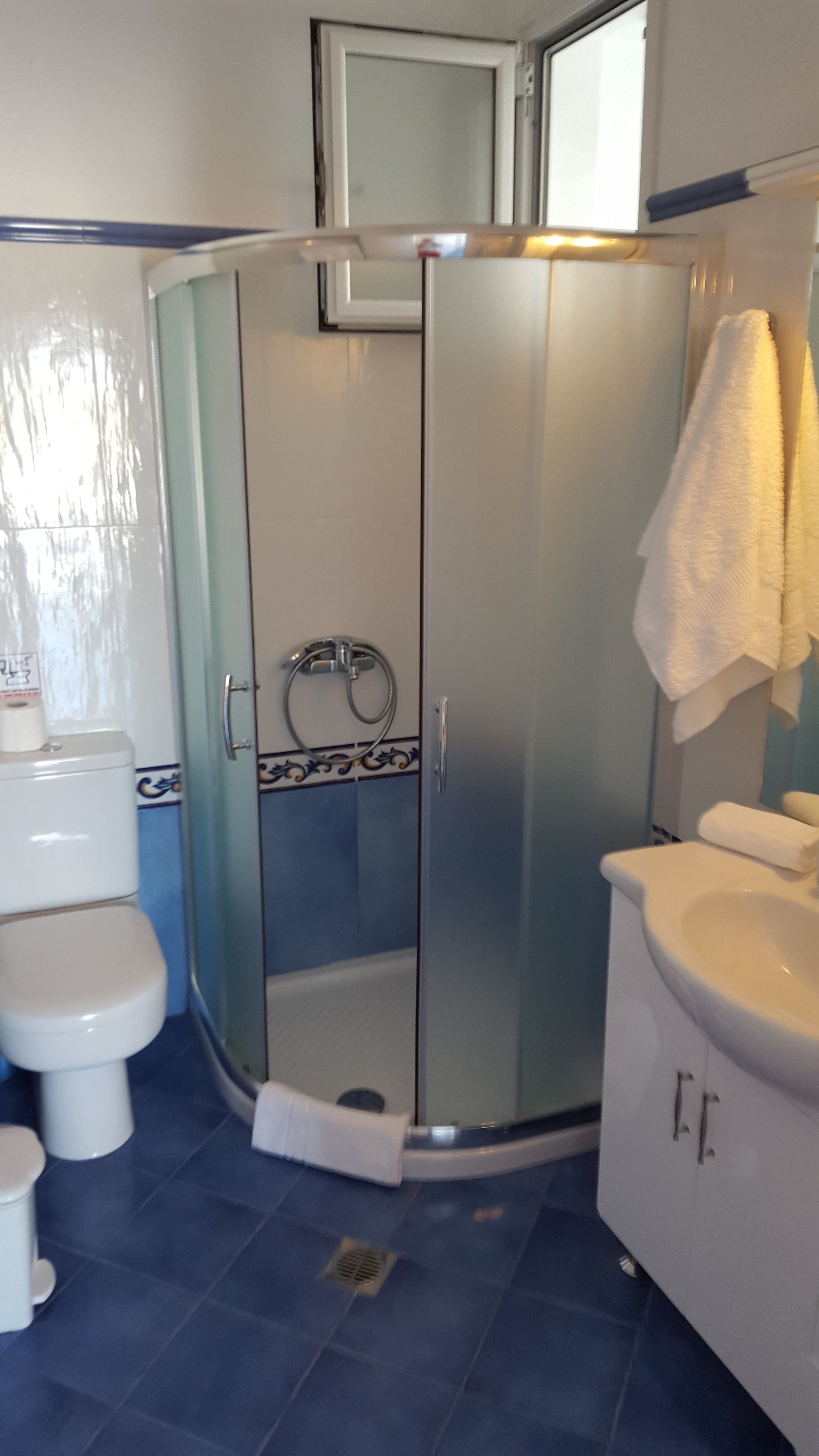 A bathroom with a glass-enclosed shower, a toilet, and a sink.