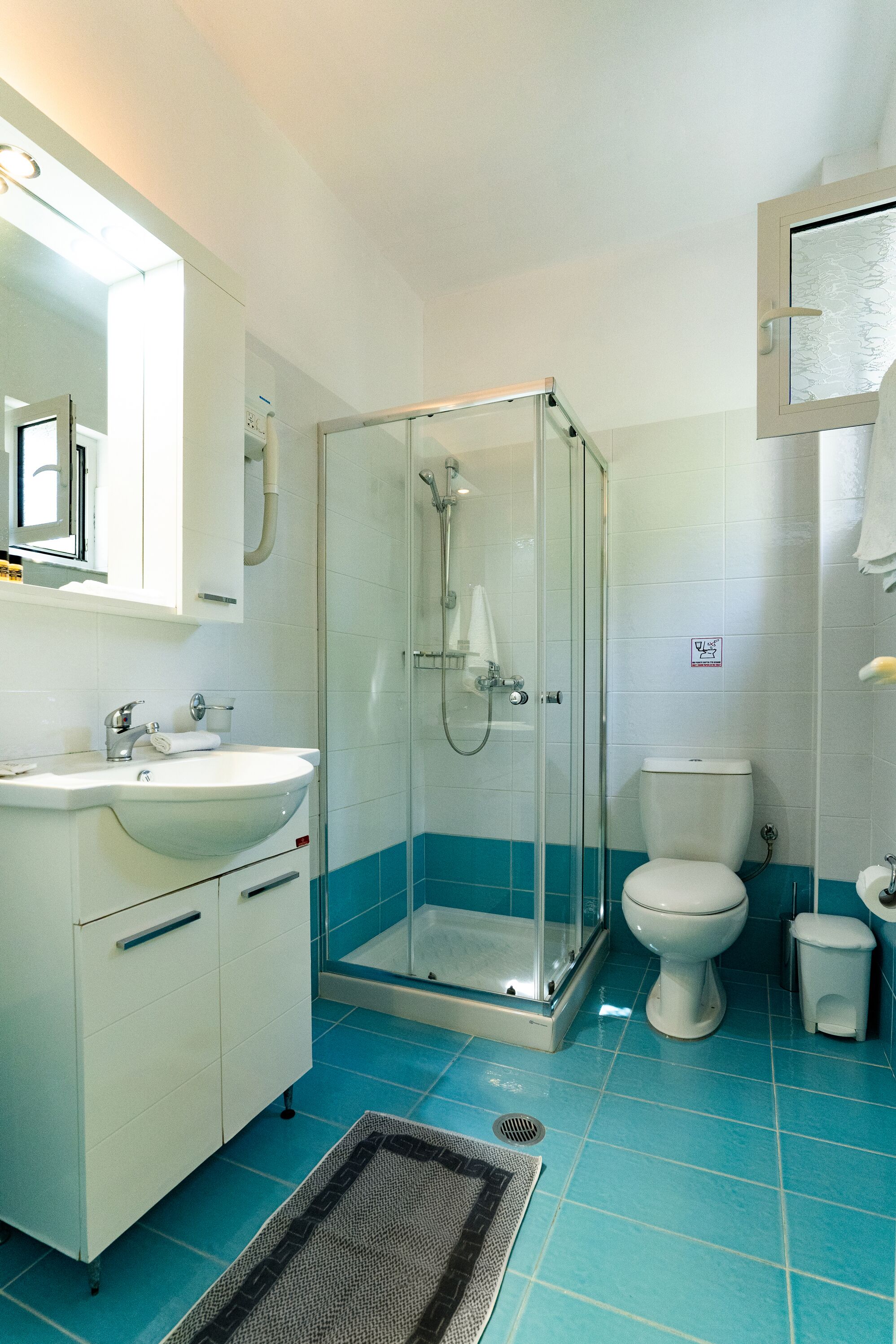 A bathroom with a glass-enclosed shower, a white sink, and a toilet.