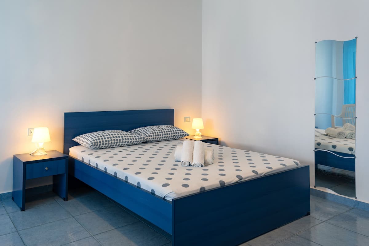 A neatly made bed with a polka dot bedspread, two pillows, and two bedside lamps.