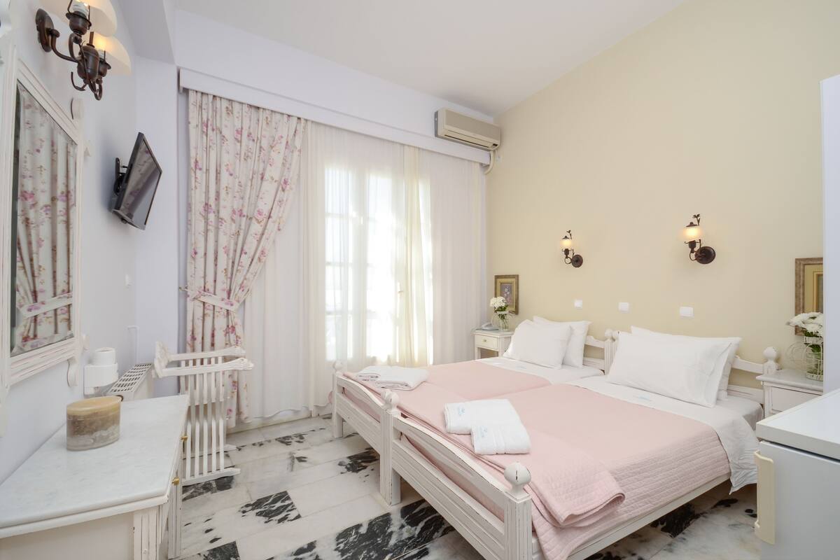 Un dormitorio ordenado con cama, mesitas de noche, una silla y un escritorio.