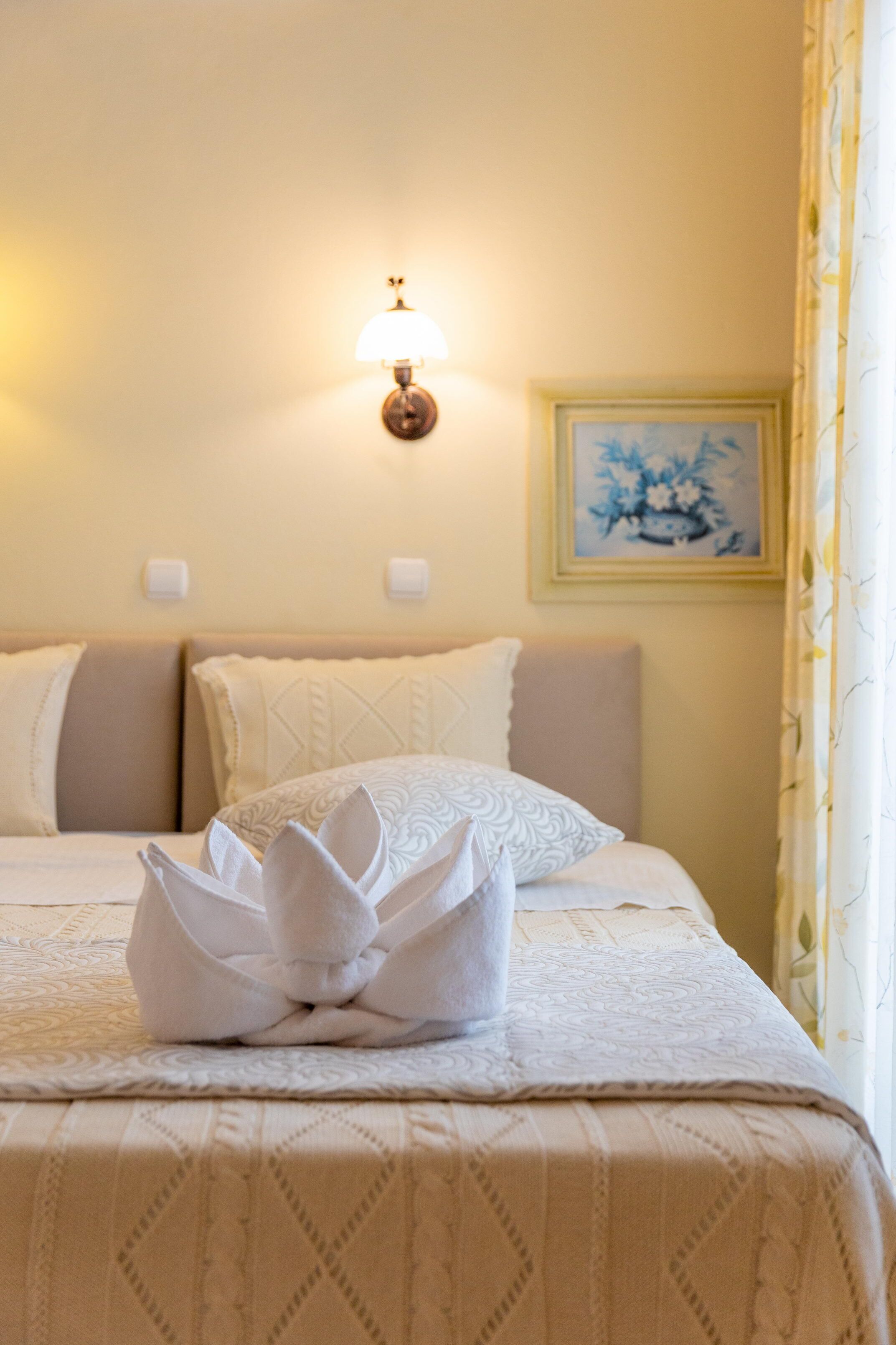 A neatly made bed with a folded towel and a wall-mounted light fixture.