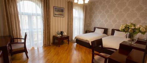 A hotel room with two beds, wooden furniture, a desk, and a chandelier.