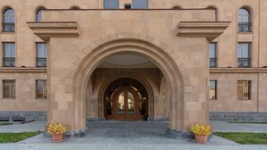 A building with a large arched entrance, multiple windows, and a central clock tower. - Latar Hotel Complex (Yerevan)