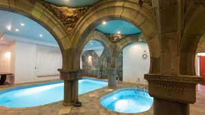 An indoor swimming pool with stone arches, a stone floor, and a stone wall in the background. - Latar Hotel Complex (Yerevan)