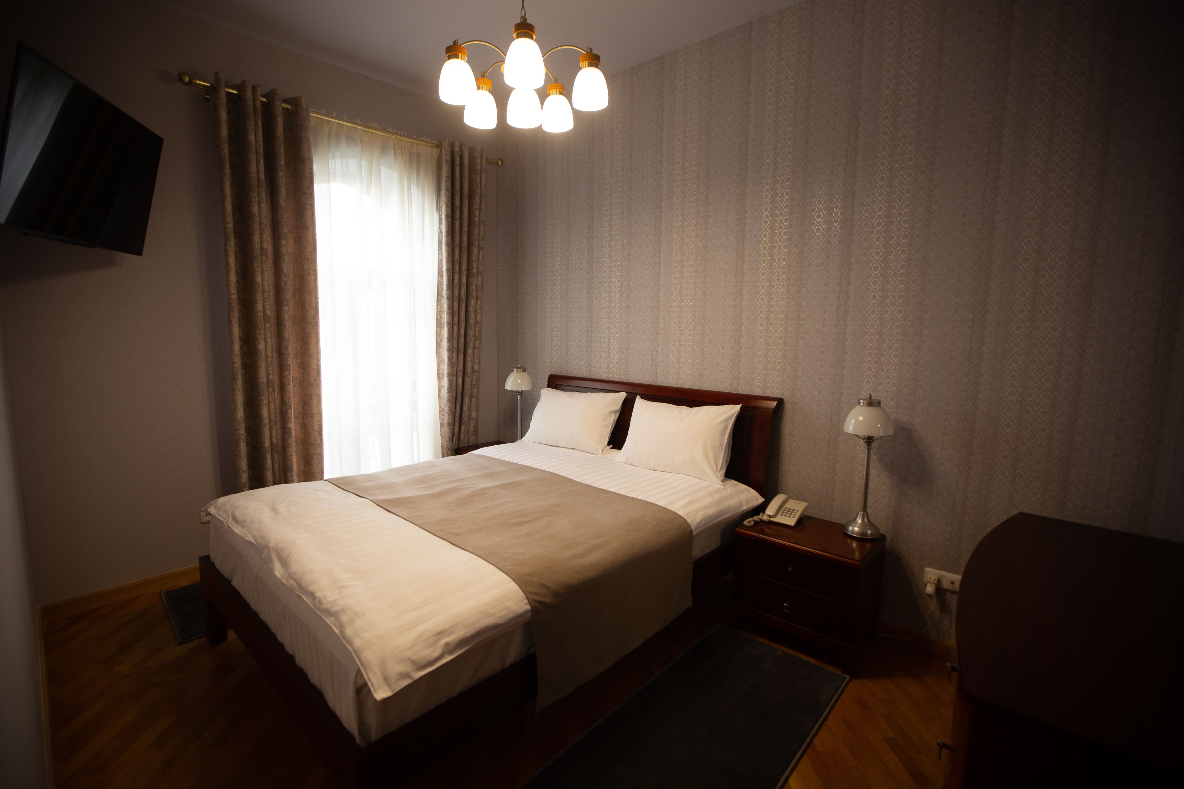 Une chambre d’hôtel avec un grand lit, des lampes de chevet, un téléviseur à écran plat et un plancher en bois.