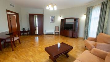 Una sala de estar con una mesa de centro de madera, un sofá color beige y un televisor.