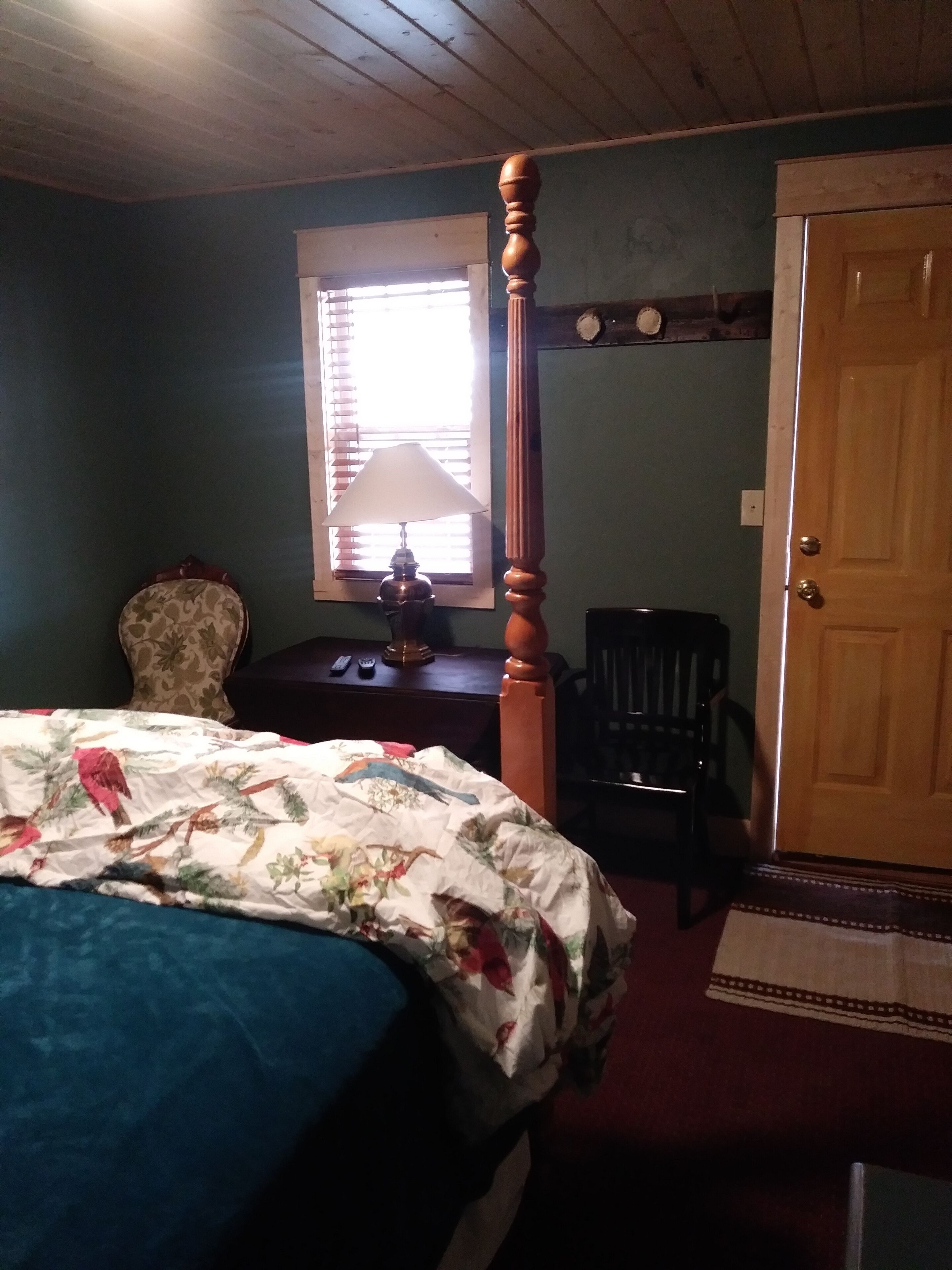 Une chambre à coucher avec un lit, une table de chevet, une lampe, une chaise et une porte.