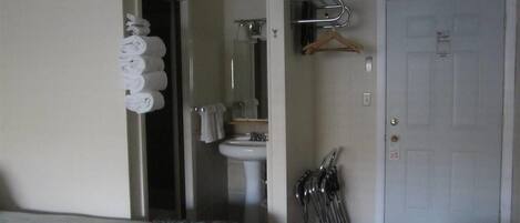A hotel room with a bed, a bathroom with a sink and mirror, and a door.