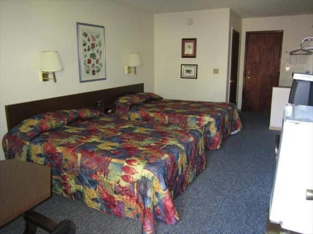 Habitación de hotel con dos camas, un escritorio, una silla, un televisor y una puerta.