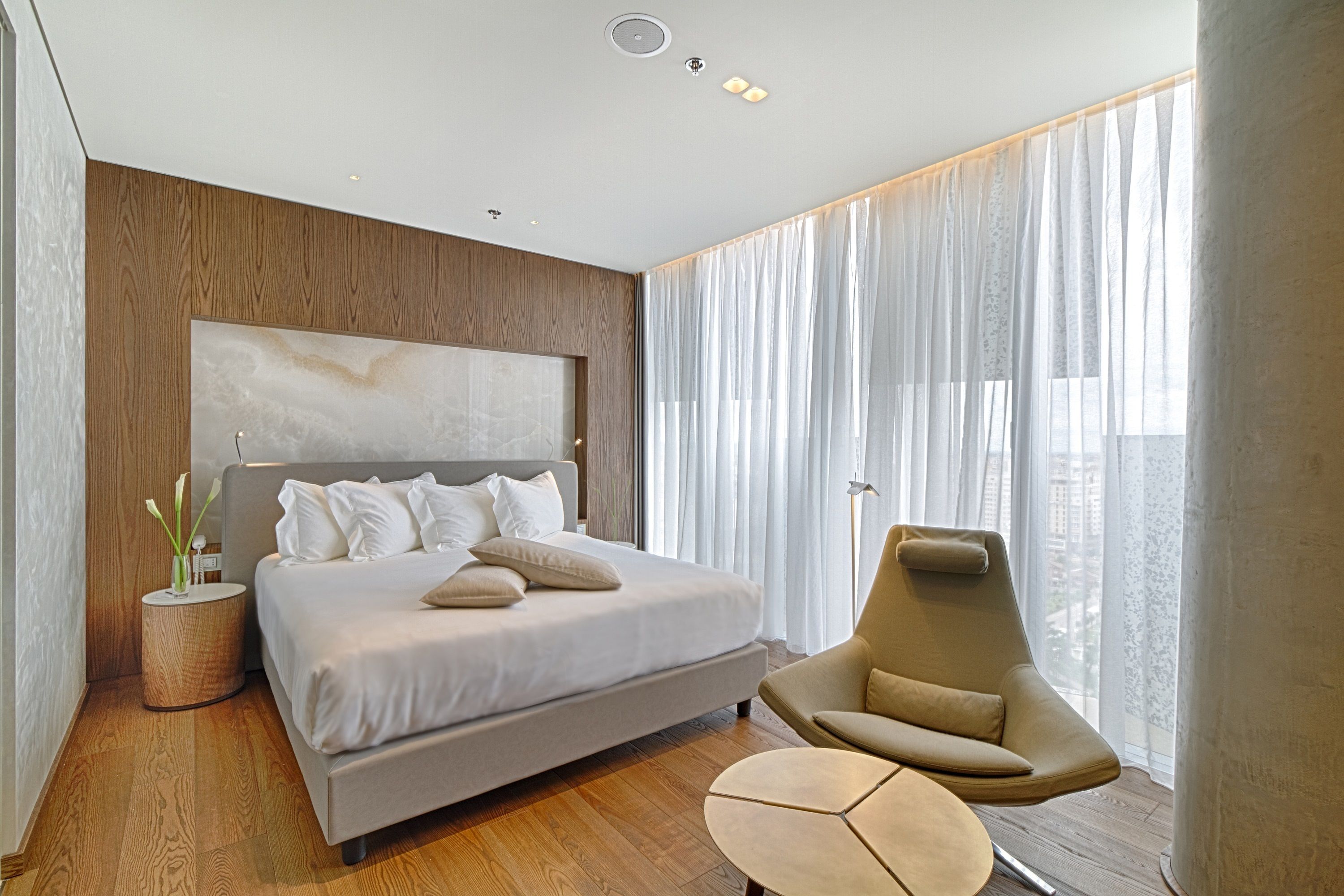 A modern bedroom with a large bed, a sofa, and a small table.
