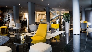 A modern lobby with a central seating area, a staircase, and a reception desk.