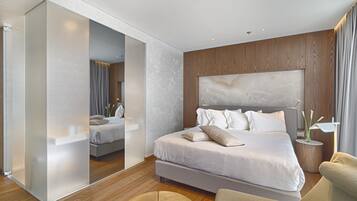 Ein modernes Hotelzimmer mit einem großen Bett, einem Holzkopfstück, einem runden Beistelltisch und einem Spiegel.
