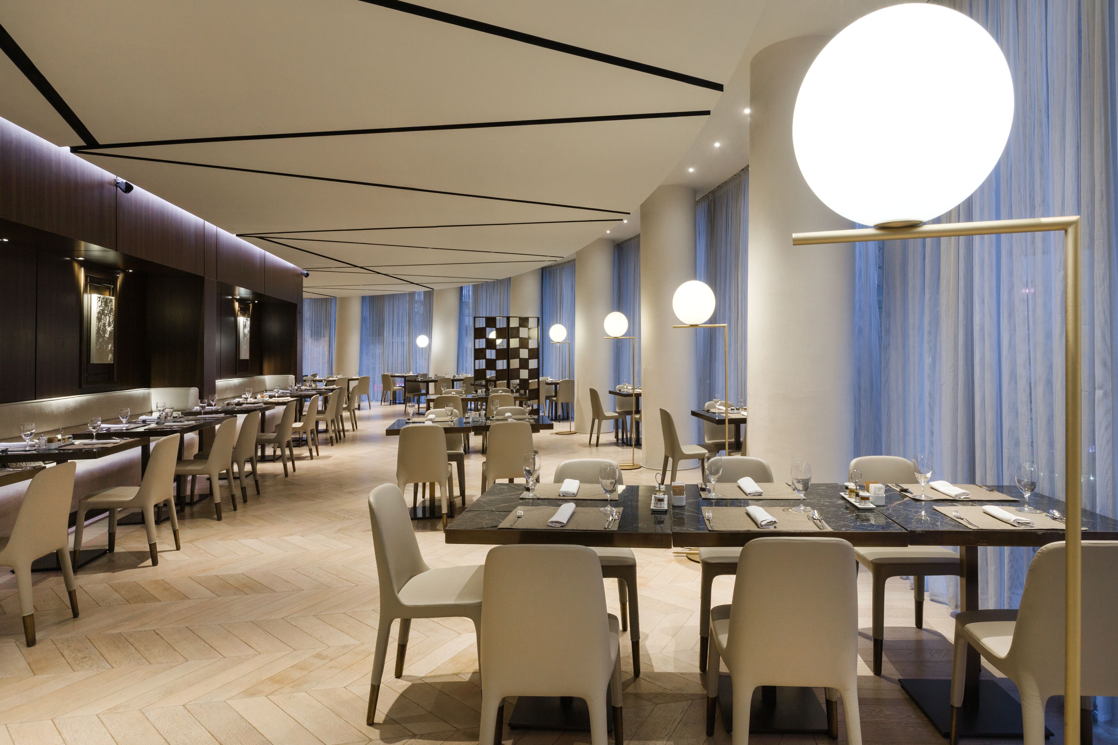 Un restaurante amplio con numerosas mesas y sillas, un estampado de cuadros en la pared y un diseño de techo moderno.