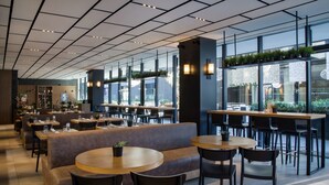 A modern restaurant with a mix of seating options including round tables, booths, and high tables.