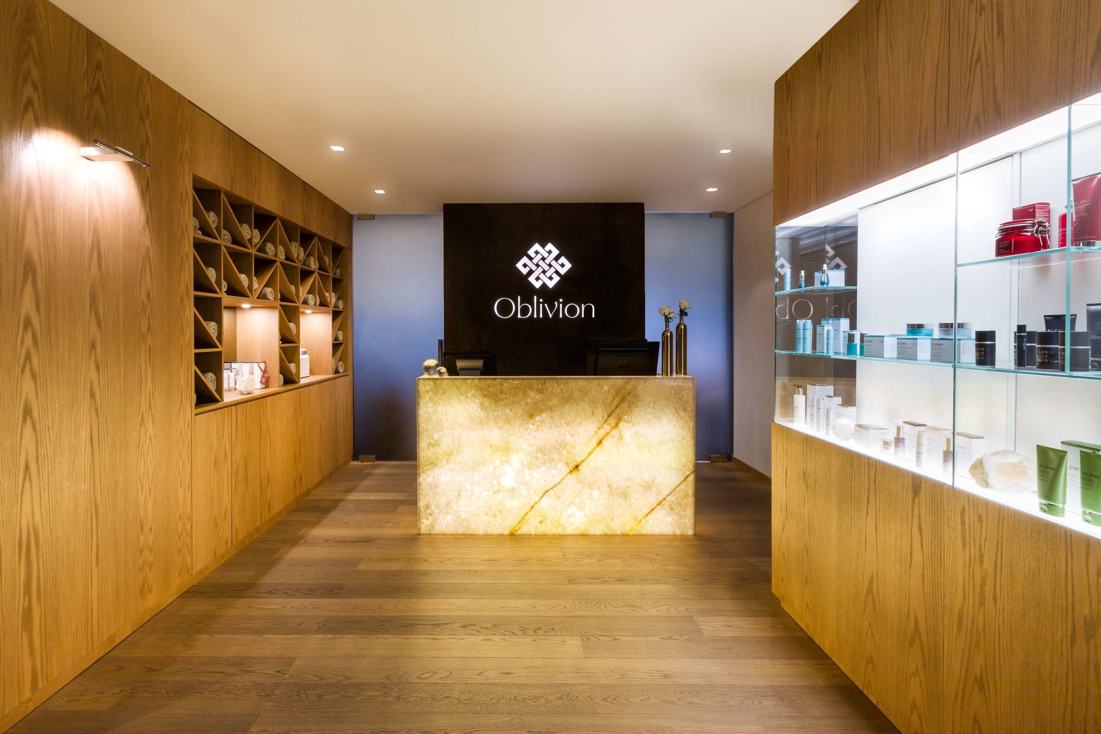 A reception area with a wooden reception desk, a wall-mounted sign with the name 'Oblivion', and shelves with various items.