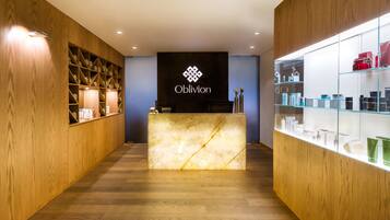 A reception area with a wooden reception desk, a wall-mounted sign with the name 'Oblivion', and shelves with various items.