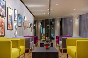 Un vestíbulo de hotel con mobiliario moderno, obras de arte enmarcadas en las paredes y un árbol de Navidad al fondo.