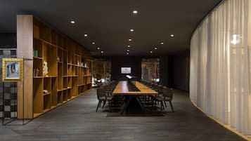 Una larga mesa de madera con sillas en un ambiente moderno de biblioteca.
