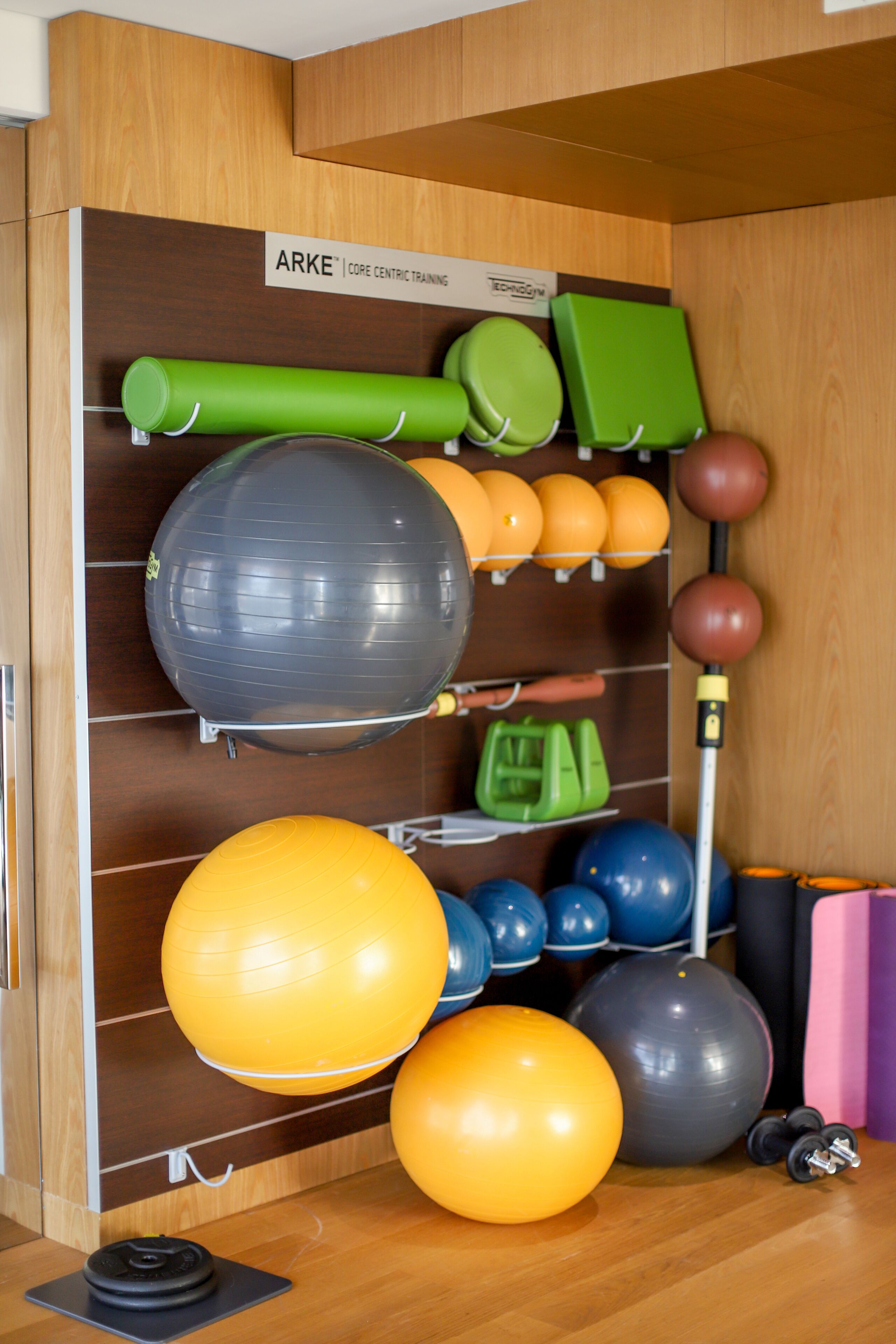 A gym with exercise equipment including balls, medicine balls, and a bench.