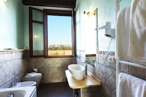 A bathroom with a large window, a sink, a toilet, and a towel rack.