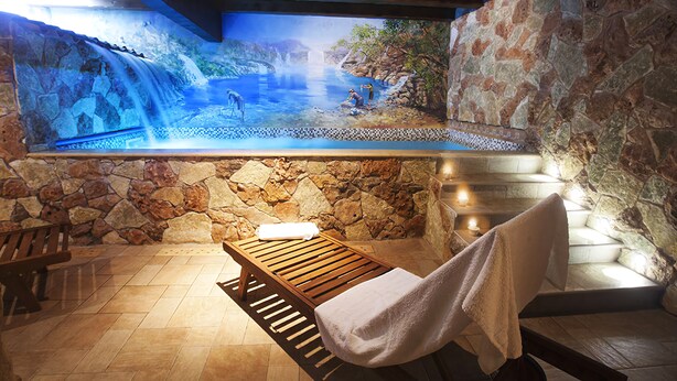 Ein Wellnessbereich mit einer Steinwand, einer Holzbank und einer Bank mit Handtuch.