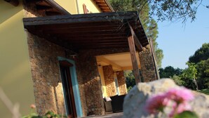 Ein Steinhaus mit überdachter Terrasse und einer Tür.