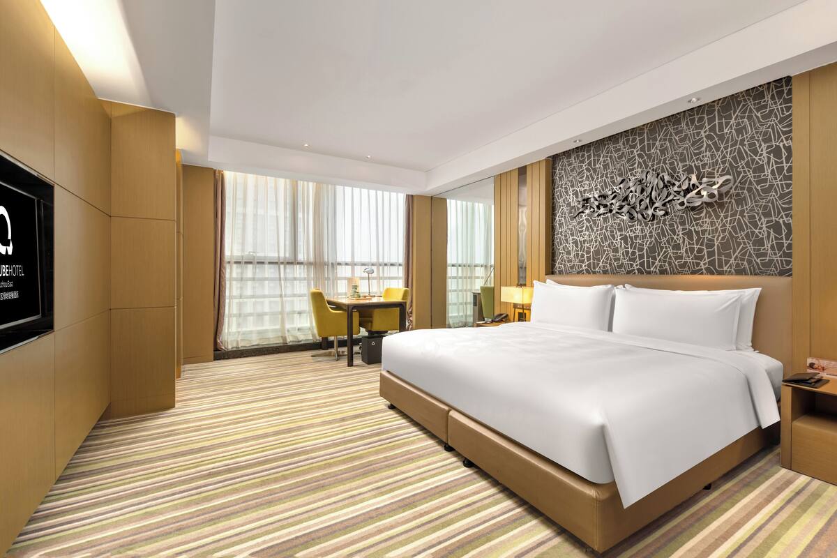 Une chambre d’hôtel avec un grand lit, un bureau, une chaise et un téléviseur.