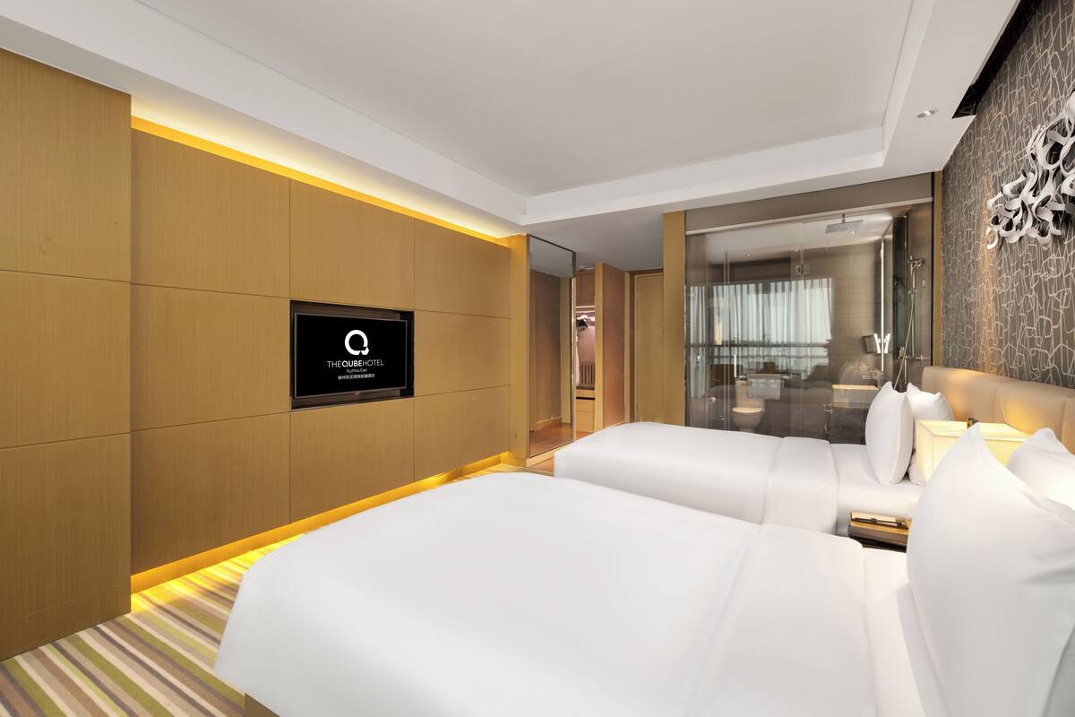Une chambre d’hôtel moderne équipée de deux lits, d’un téléviseur à écran plat et d’un miroir.