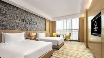 Ein Hotelzimmer mit zwei Betten, einem Fernseher, einem Schreibtisch und einem fensterbepflanzten Fenster.