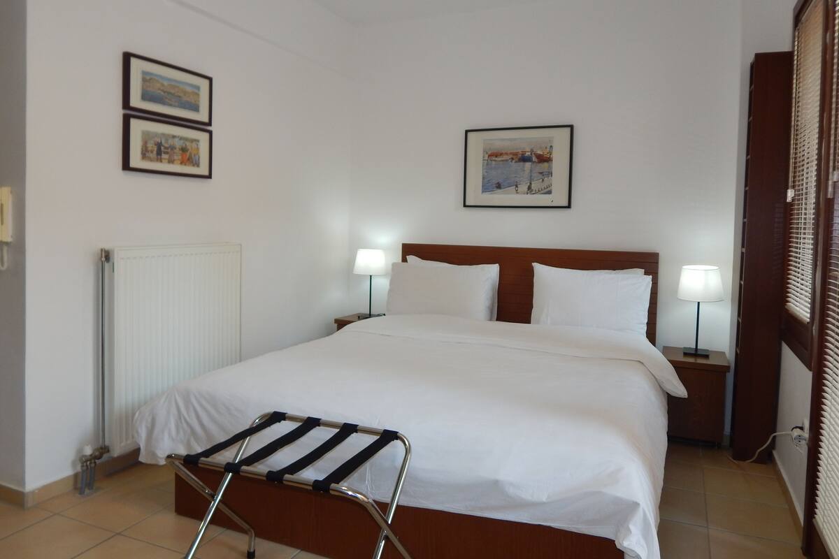 Ein Hotelzimmer mit einem großen Bett, zwei Nachttischen mit Lampen, einer Heizung und zwei gerahmten Bildern an der Wand.