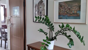 Een eetgedeelte met een houten tafel en stoelen, een potplant en twee ingelijste foto’s aan de muur.