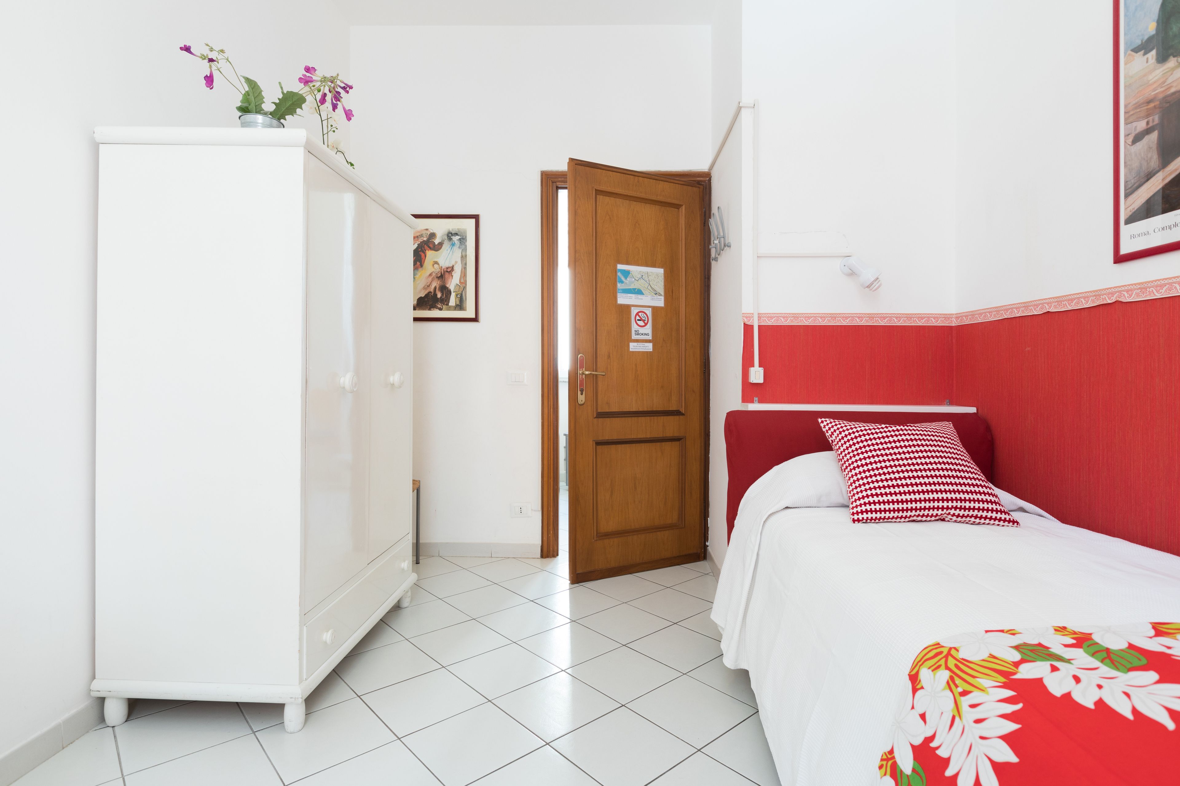 Un dormitorio con cama, armario, puerta y un cuadro colgado en la pared.