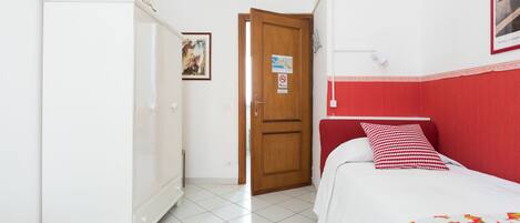 Un dormitorio con cama, armario, puerta y un cuadro colgado en la pared.