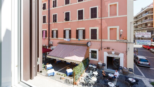 A pink building with a restaurant patio, outdoor seating, and a sign for 'Antica Trattoria'. - B&B Piazza Fratti (Civitavecchia)