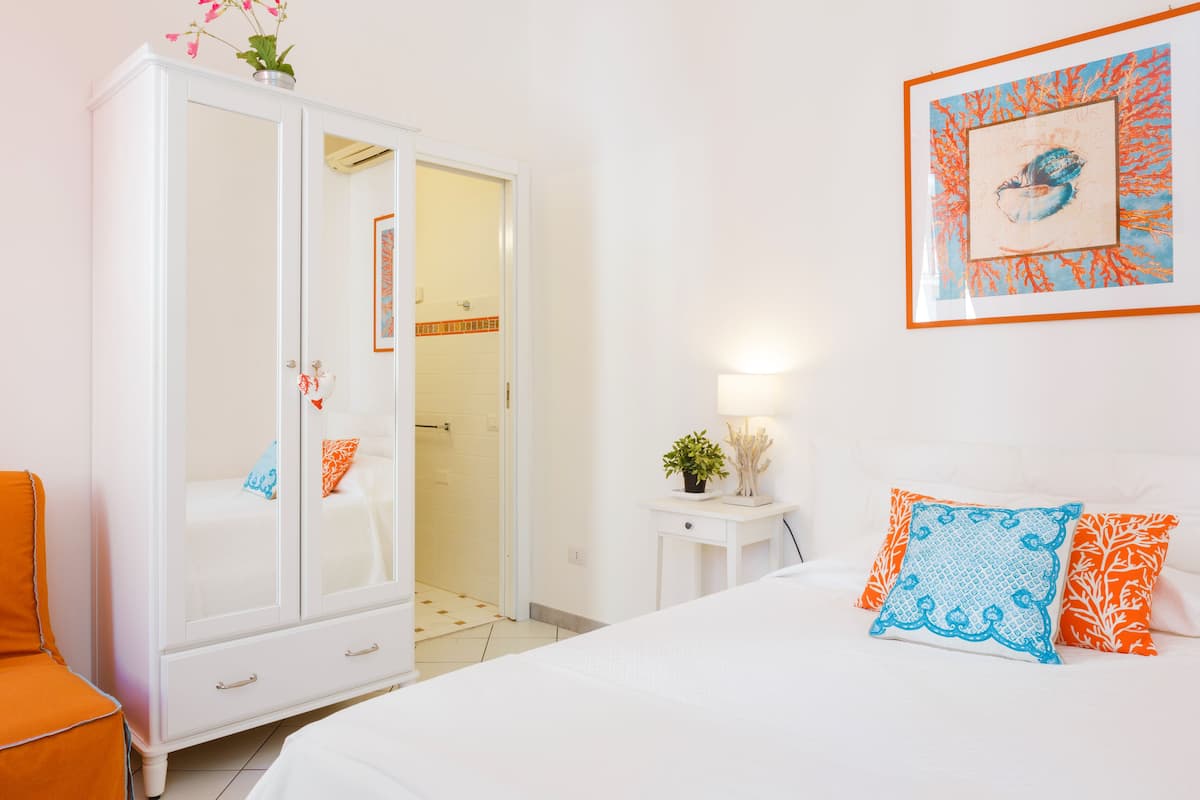 A bedroom with a bed, a wardrobe, a nightstand, and a framed picture on the wall.