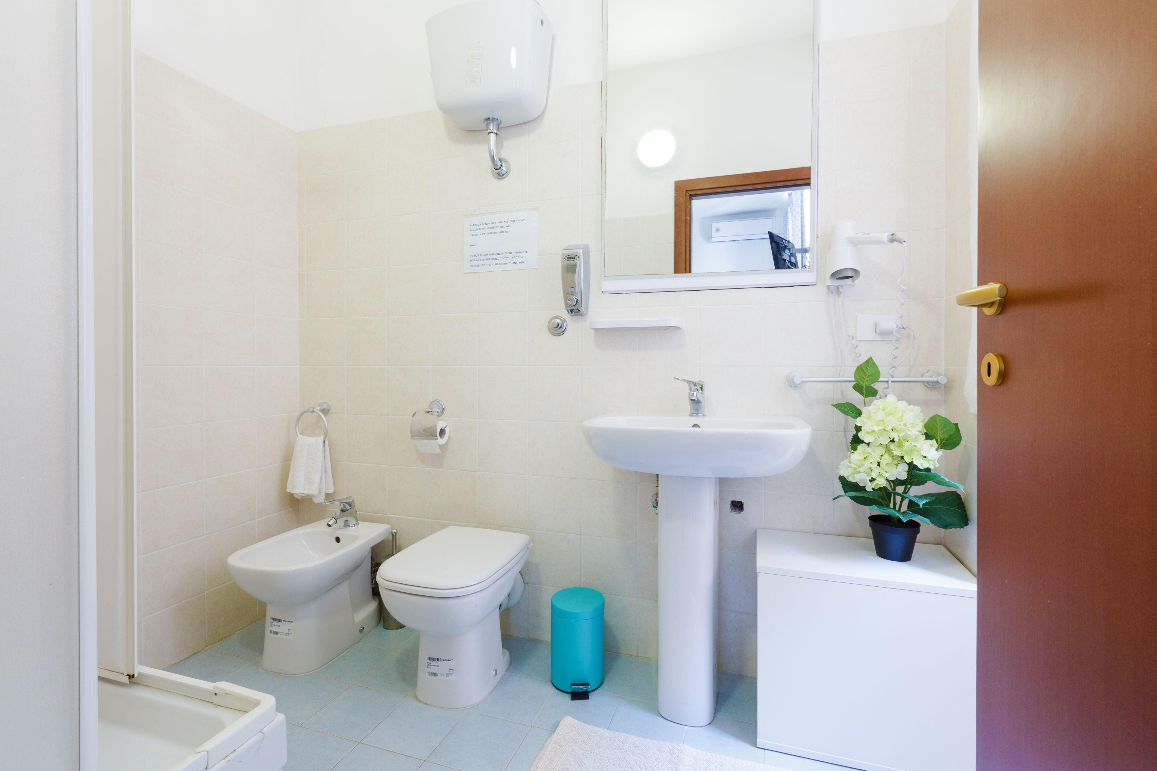 A bathroom with a bidet, toilet, sink, and a mirror.