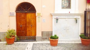A building facade with a wooden double door, a plaque, and a marble plaque above a fireplace. - B&B Piazza Fratti (Civitavecchia)
