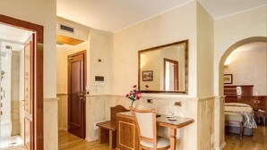 A hotel room with a wooden desk, a chair, a mirror, a bed, and a bathroom with a shower. - Pantheon Rooms (Rome)