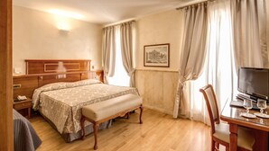 A hotel room with a wooden bed, a bedside table, a desk with a TV and glasses, and a window with curtains. - Pantheon Rooms (Rome)