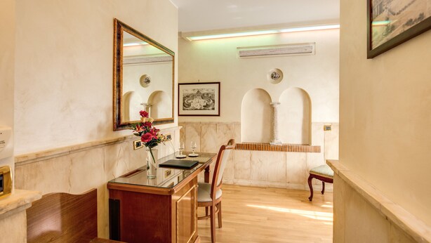 A dining area with a marble countertop, a wooden chair, and a table with a vase of flowers. - Pantheon Rooms (Rome)