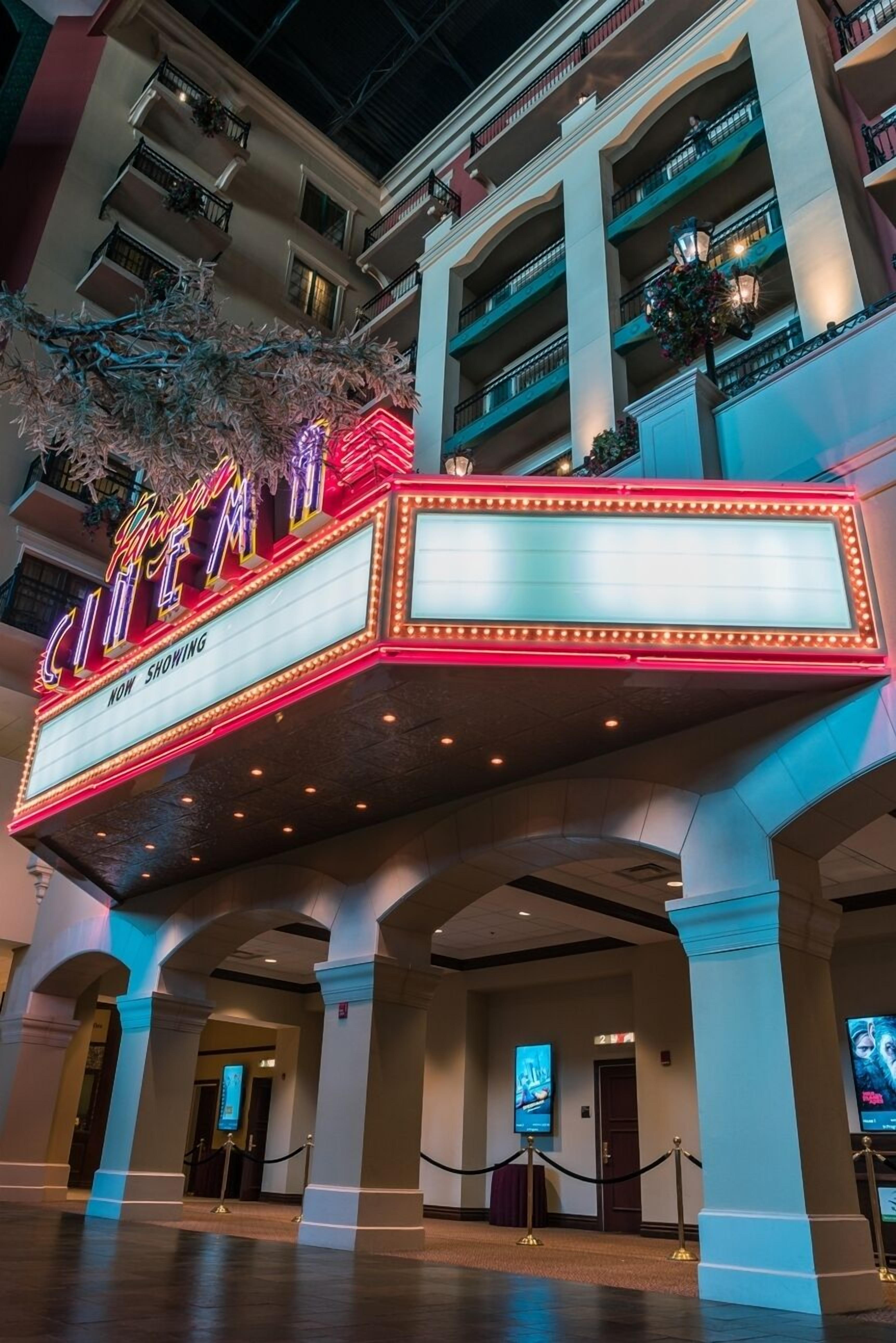 Un cartel de cine exhibe la frase 'Now Showing', indicando que se trata de un cine dentro de un hotel.
