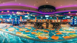 Un grand casino, très bien éclairé, avec de nombreuses tables de jeux et des machines à sous.