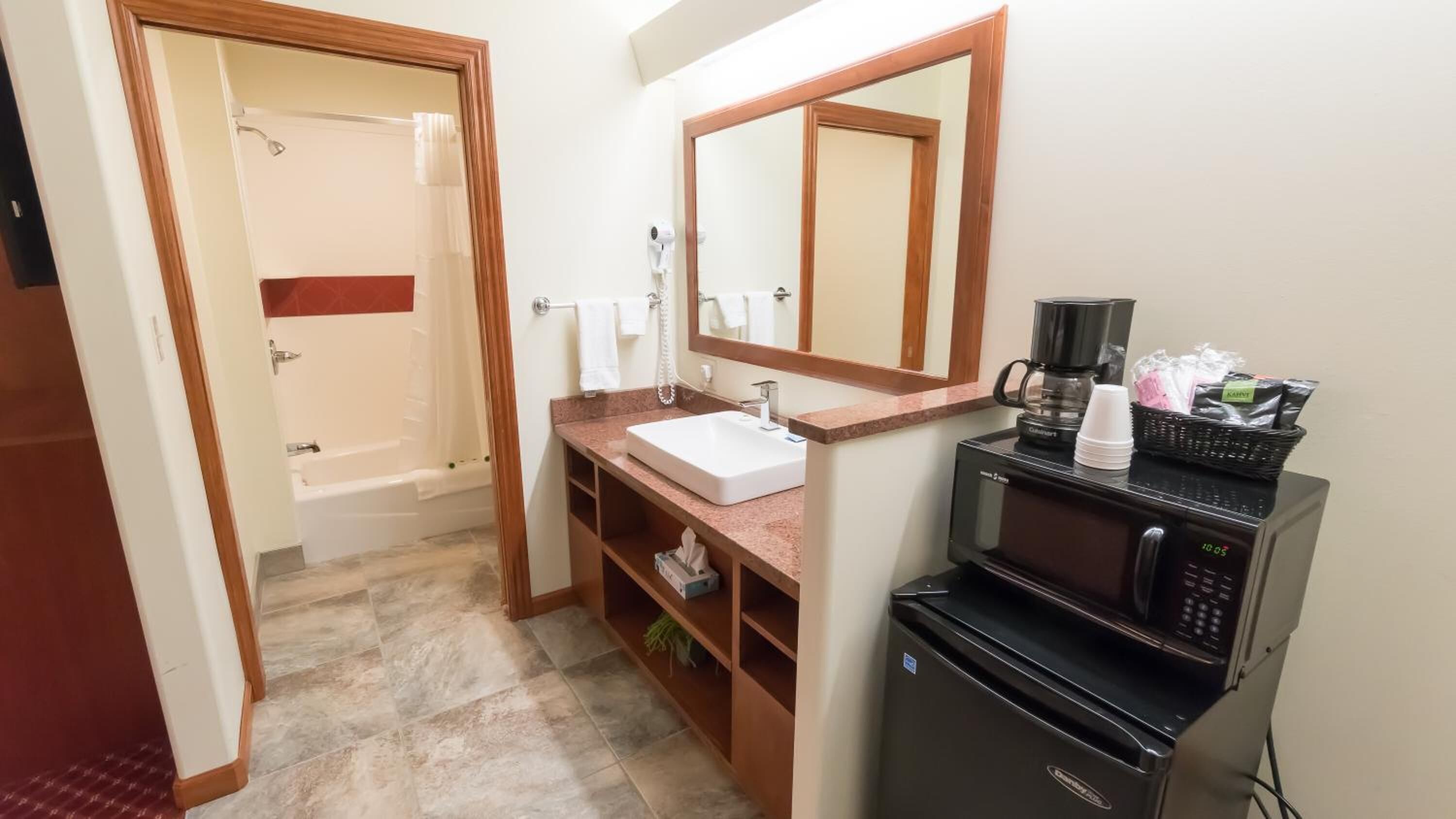 Baño con lavamanos, espejo y cafetera.