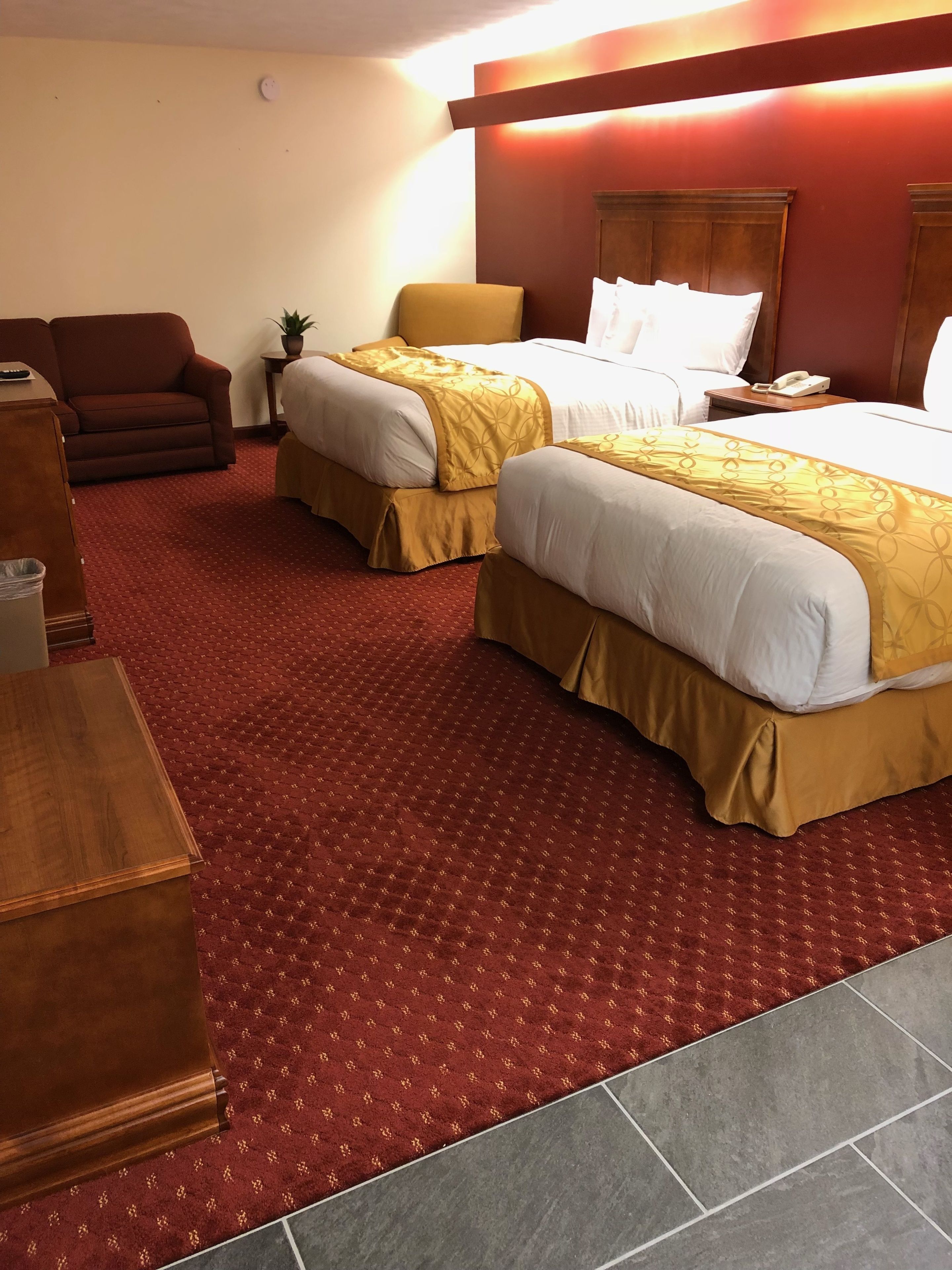A hotel room with two beds, a sofa, a small table, and a telephone.
