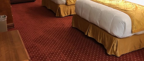 Een hotelkamer met twee bedden, een slaapbank, een klein tafeltje en een telefoon.