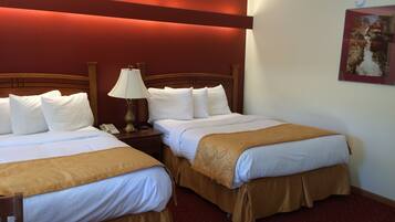 Una habitación de hotel con dos camas, una mesita de noche con lámpara y un cuadro en la pared.