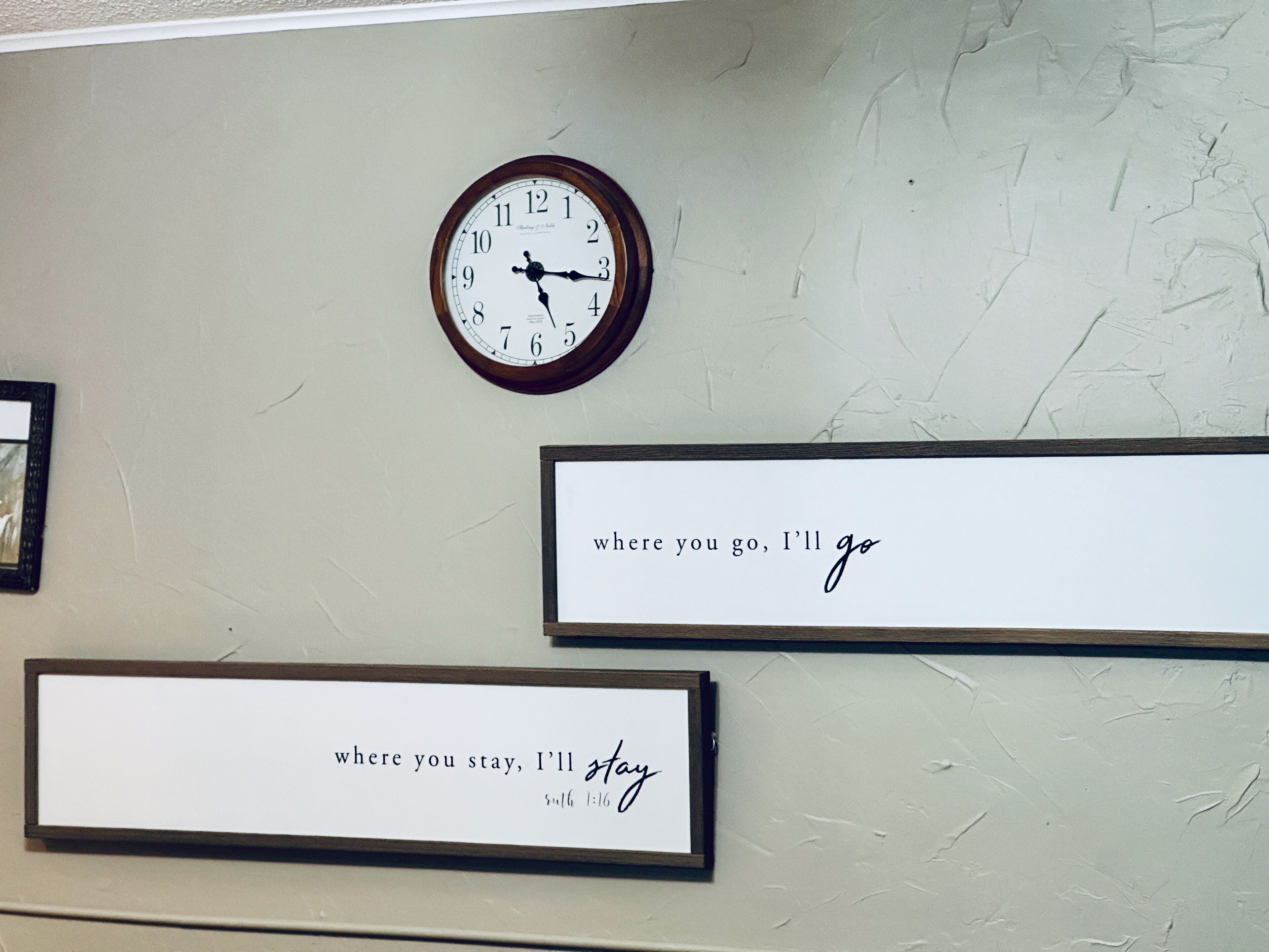 A wall with a clock and two framed inspirational quotes.