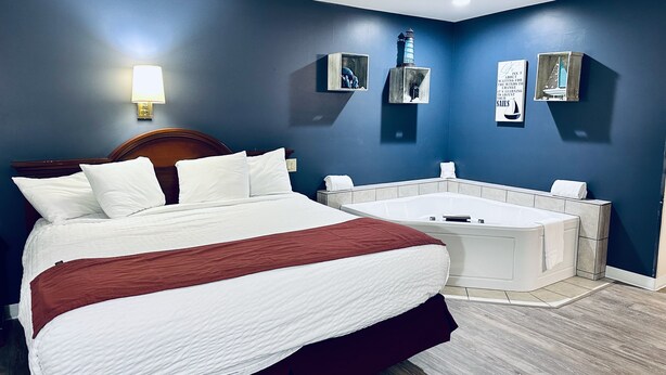 Habitació d'hotel amb un llit gran, una zona de seients petita que inclou una banyera blanca, i una làmpada penjant a la paret.
