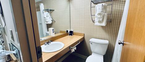 A bathroom with a wooden vanity, a sink, a toilet, and a towel rack.